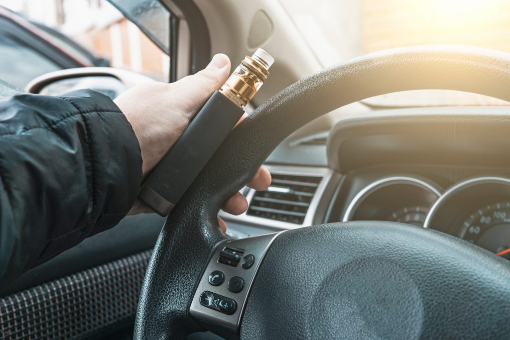 Vape device in male hand on car steering wheel - Guski ∙ Such - Rechtsanwälte Karlsruhe E-Zigarette Steuer